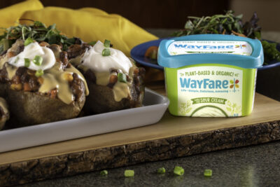 WayFare Dairy Free Sour Cream packaging sitting next to a baking sheet of loaded baked potatoes.
