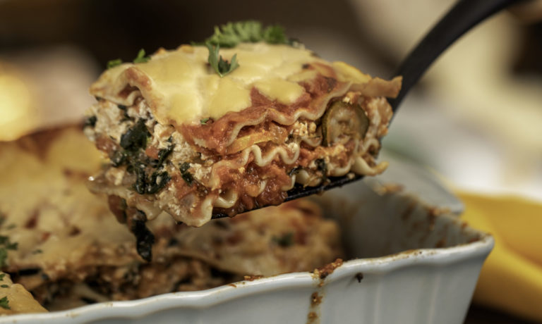 A Vegan Lasagna made with WayFare ingredients is coming out of the pan on a spatula.