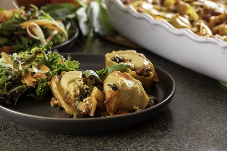 Stuffed Shells made with WayFare Dairy Free Cheddar displayed on a plate paired with a fresh house salad.