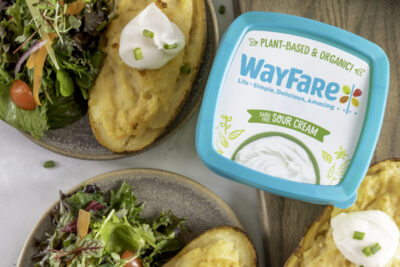 WayFare Dairy Free Sour Cream packaging sitting next to a plate of Twice Baked Potatoes and a house salad.
