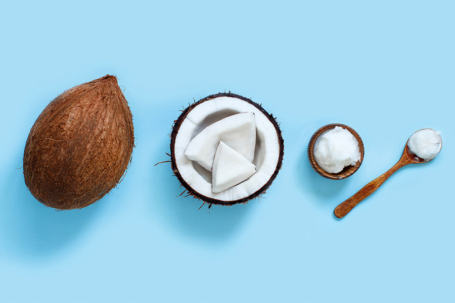 From left to right, a full coconut, a split open coconut, coconut paste, and coconut oil.